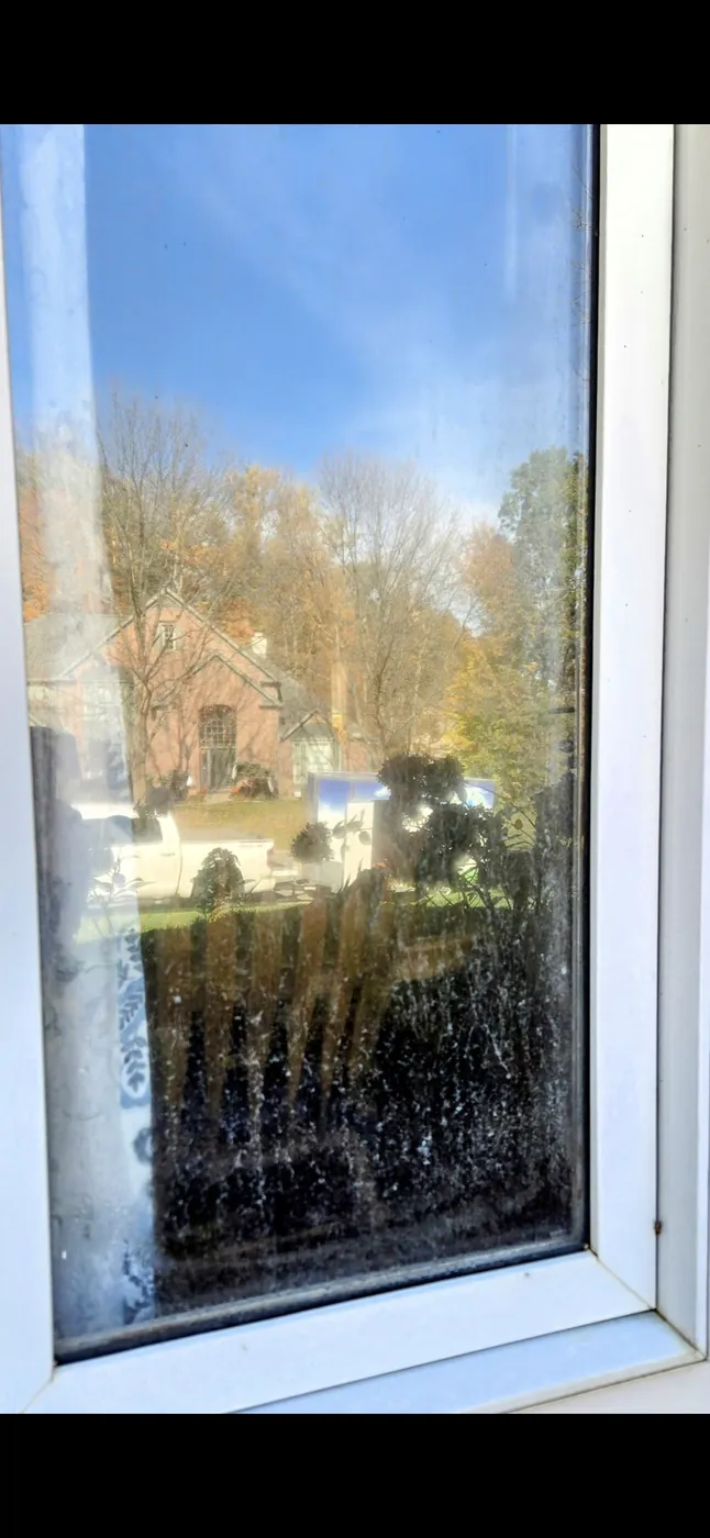 Window glass clouded with chalky hard water mineral stains before cleaning