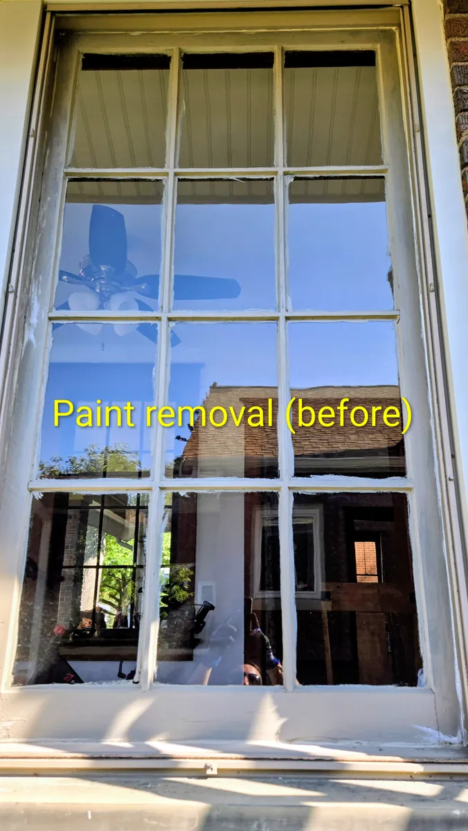 Window pane speckled with dried paint overspray before Down to Earth's restoration clean