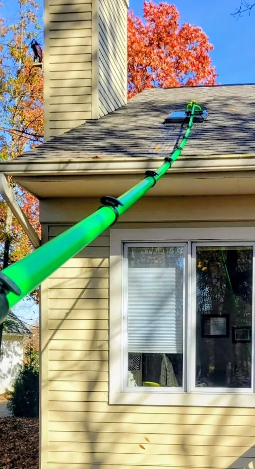 Down to Earth cleaning a rooftop skylight from outside with a water-fed extension pole