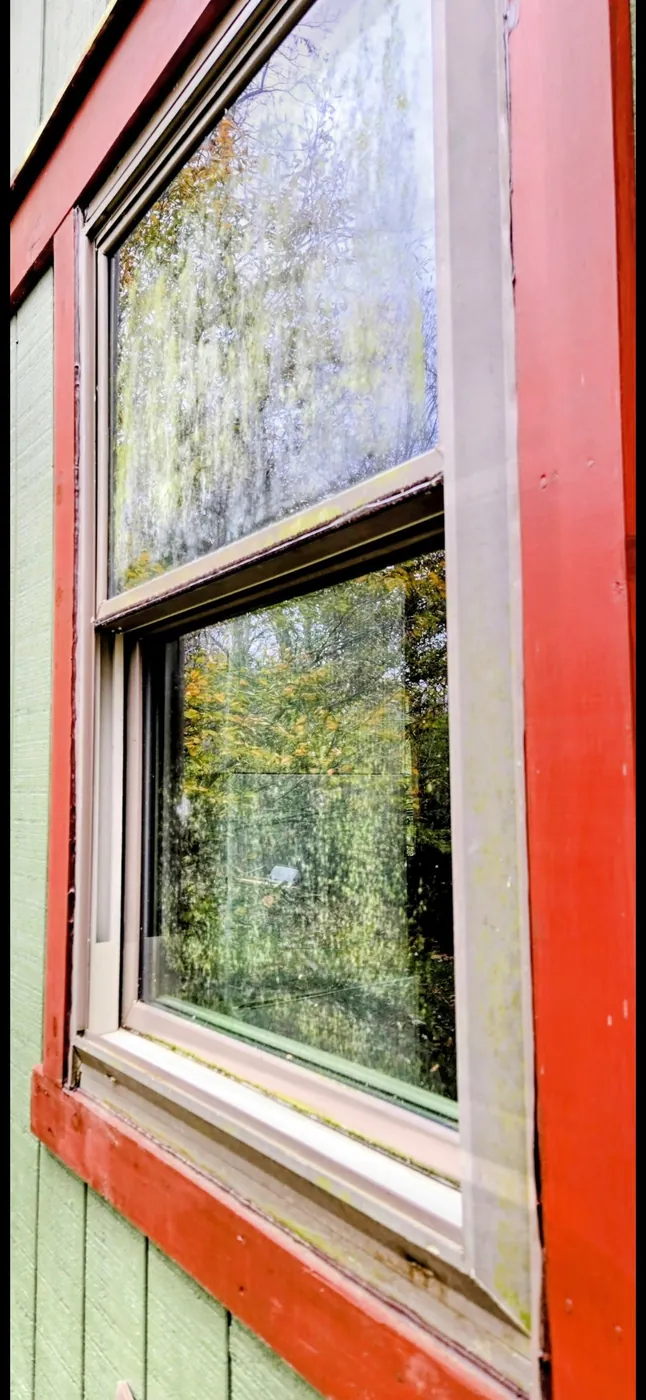 Exterior window with a hazy, grimy film of dirt and water spots before cleaning