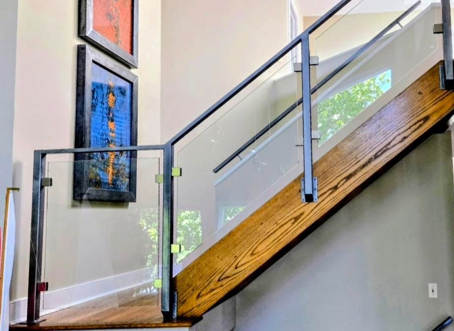 Sunlit modern staircase with a streak-free glass railing and clean window — interior window cleaning by Down to Earth
